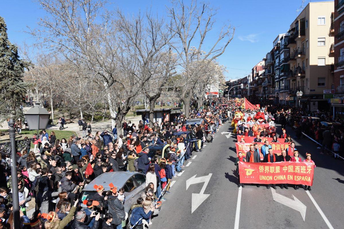 Desfile del Año Nuevo chino por una avenida de Usera, con pancartas rojas y el público detrás de las vallas